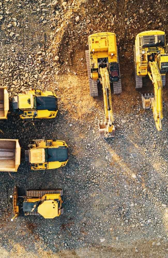 Aerial view of construction vehicles on gravel site.