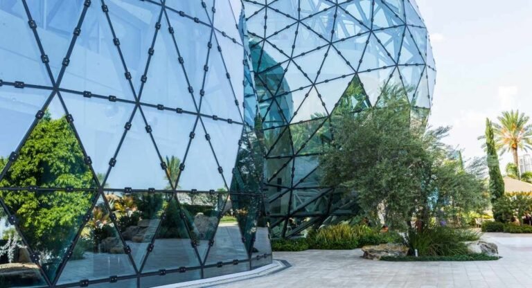 Modern glass building with geometric patterns and trees.