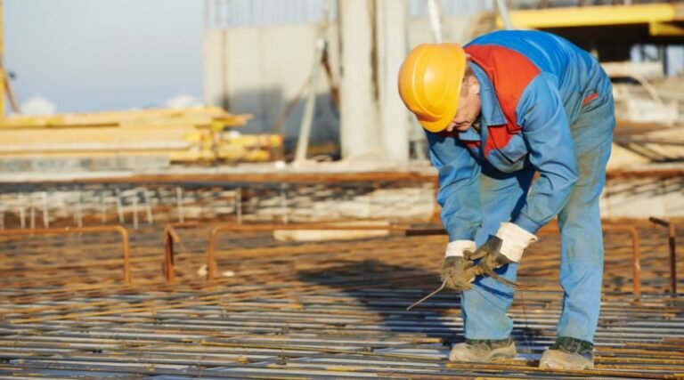 Construction worker securing steel rebars at site.