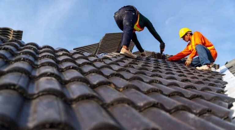 Workers installing roof tiles on a sunny day.