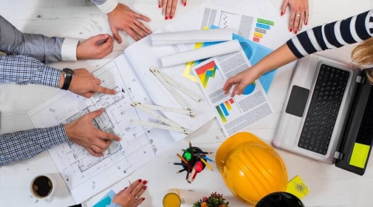 Team discussing architectural plans and charts on table.