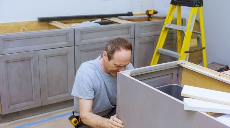 Man assembling kitchen cabinets during renovation.